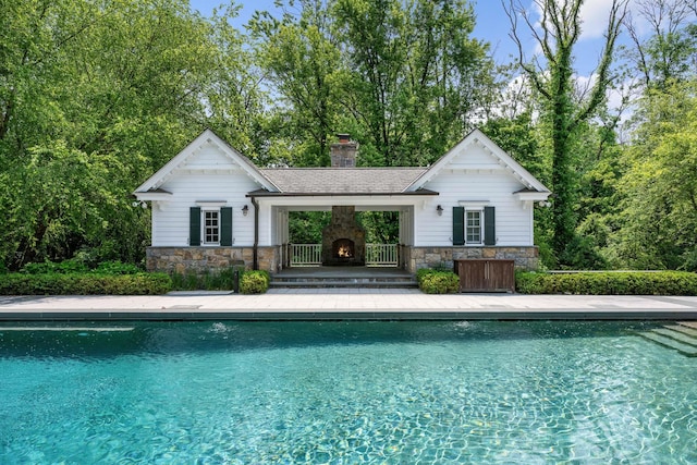 21 Dorann Rd, Purchase, NY 10577 - swimming pool with a warm lit fireplace, an exterior structure, an outdoor structure, a patio, and view of wooded area