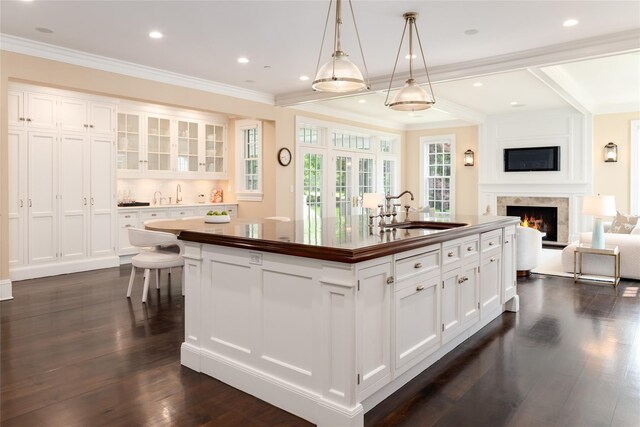 21 Dorann Rd, Purchase, NY 10577 - kitchen with a center island with sink, white cabinetry, a lit fireplace, open floor plan, and ornamental molding