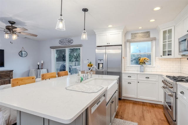 10 Bradish Ln, Babylon, NY 11702 - kitchen featuring appliances with stainless steel finishes, a kitchen bar, light countertops, light wood-style floors, and tasteful backsplash
