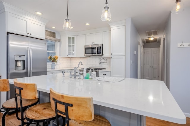 10 Bradish Ln, Babylon, NY 11702 - kitchen featuring stainless steel appliances, backsplash, white cabinets, a spacious island, and decorative light fixtures