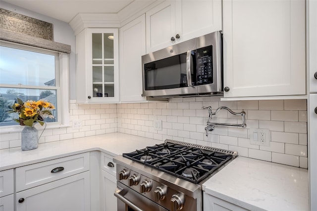 10 Bradish Ln, Babylon, NY 11702 - kitchen featuring stainless steel appliances, white cabinetry, glass insert cabinets, tasteful backsplash, and light stone counters