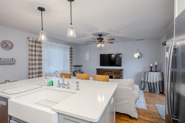 10 Bradish Ln, Babylon, NY 11702 - kitchen featuring freestanding refrigerator, a ceiling fan, wood finished floors, a center island with sink, and hanging light fixtures