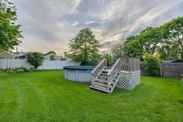 10 Bradish Ln, Babylon, NY 11702 - yard at dusk with a fenced backyard, a wooden deck, and stairway