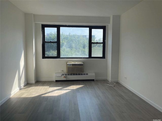 83-60 118th St Unit 7K, Kew Gardens, NY 11415 - spare room featuring wood finished floors, a wall mounted air conditioner, a baseboard radiator, and radiator heating unit