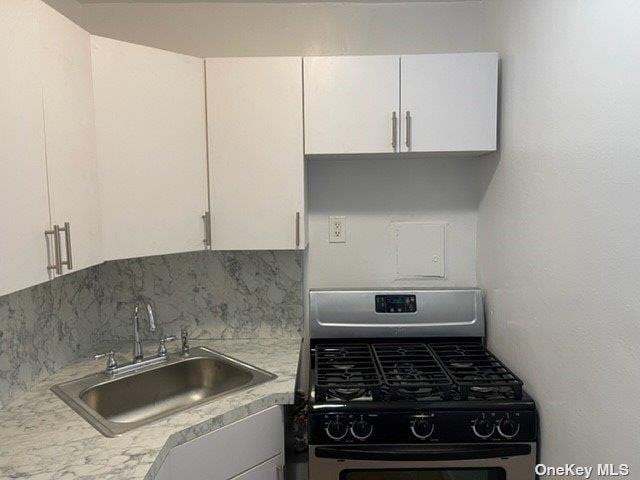 83-60 118th St Unit 7K, Kew Gardens, NY 11415 - kitchen featuring range with gas stovetop, white cabinets, light countertops, and backsplash