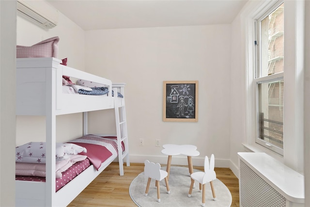 1180 Grant Ave, Bronx, NY 10456 - bedroom featuring a wall mounted air conditioner, wood finished floors, and baseboards