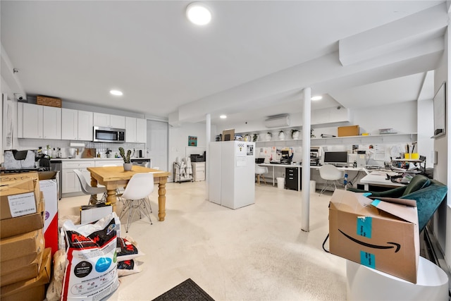 1180 Grant Ave, Bronx, NY 10456 - kitchen with stainless steel microwave, a wall mounted air conditioner, white cabinetry, recessed lighting, and freestanding refrigerator