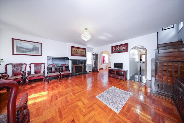 95-15 243rd St, Floral Park, NY 11001 - living room with a tiled fireplace, arched walkways, stairs, and a chandelier