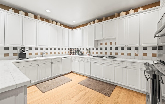 5 Hickory Ct, Manhasset, NY 11030 - kitchen featuring tile countertops, oven, tasteful backsplash, dishwashing machine, and stainless steel gas stovetop
