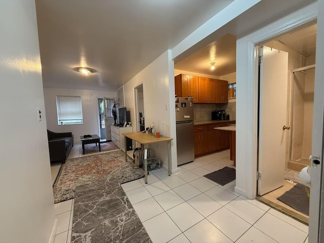 51-21 Goldsmith St, Elmhurst, NY 11373 - kitchen with freestanding refrigerator, brown cabinets, decorative backsplash, light countertops, and light tile patterned floors