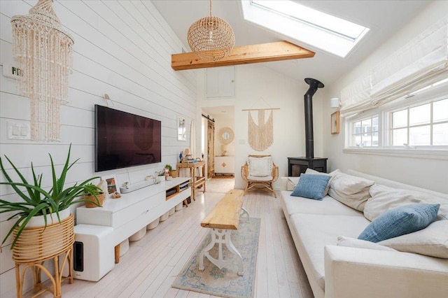 96 Alabama St, Long Beach, NY 11561 - living area featuring a wood stove, light wood-type flooring, wooden walls, high vaulted ceiling, and a skylight