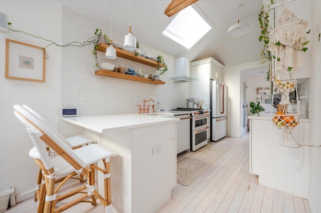 96 Alabama St, Long Beach, NY 11561 - kitchen with wall chimney exhaust hood, high end fridge, range with two ovens, a peninsula, and a breakfast bar area