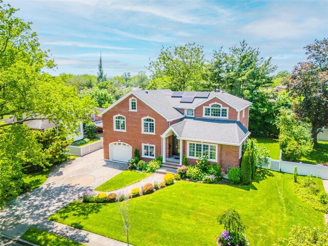 151 Birch Dr, Manhasset Hills, NY 11040 - traditional home featuring decorative driveway, a garage, brick siding, solar panels, and view of scattered trees