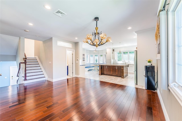 151 Birch Dr, Manhasset Hills, NY 11040 - unfurnished living room with a chandelier, light wood-style floors, stairs, and recessed lighting