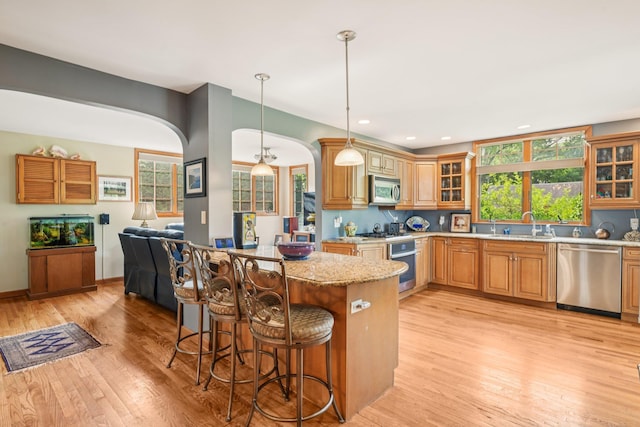54 Ogden Ave, East Williston, NY 11596 - kitchen with stainless steel appliances, arched walkways, a breakfast bar area, light wood finished floors, and glass insert cabinets