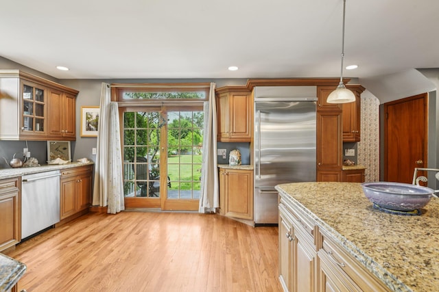 54 Ogden Ave, East Williston, NY 11596 - kitchen featuring stainless steel appliances, light wood finished floors, light stone counters, recessed lighting, and glass insert cabinets