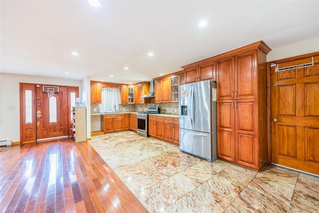 145-04 21st Ave, Whitestone, NY 11357 - kitchen with stainless steel appliances, brown cabinetry, glass insert cabinets, light countertops, and wall chimney range hood