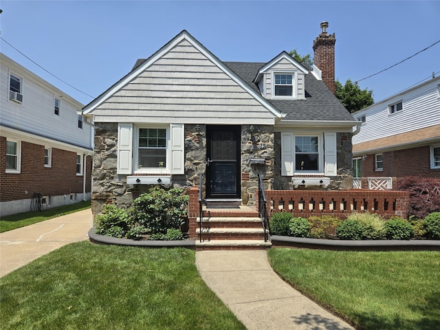 29 Irving St, Valley Stream, NY 11580 - view of front facade featuring stone siding, a chimney, a shingled roof, and a front lawn