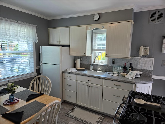 29 Irving St, Valley Stream, NY 11580 - kitchen featuring freestanding refrigerator, black gas range, white cabinets, and ornamental molding
