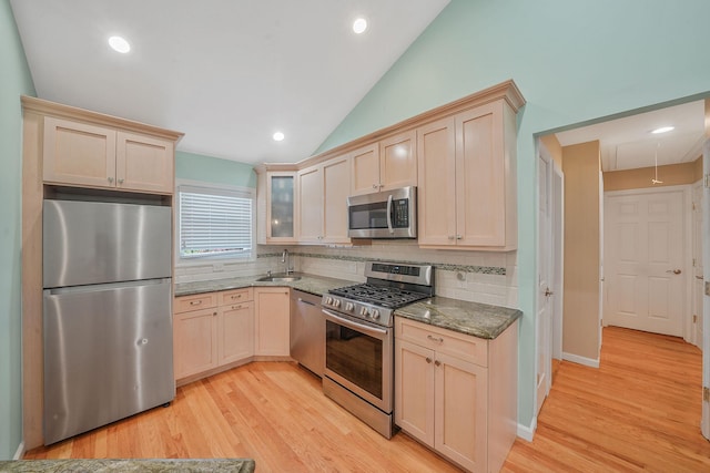123 Baker Ct, Island Park, NY 11558 - kitchen featuring stainless steel appliances, lofted ceiling, tasteful backsplash, dark stone countertops, and a sink