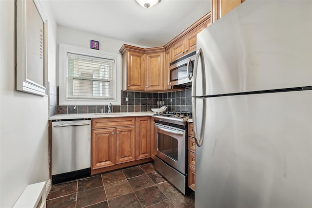 1833 Palmer Ave Unit 2C, Larchmont, NY 10538 - kitchen featuring appliances with stainless steel finishes, a sink, backsplash, stone finish flooring, and brown cabinetry