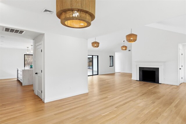 10 Lenape Rd, Southampton, NY 11968 - unfurnished living room with light wood-type flooring, a chandelier, baseboards, and a fireplace with flush hearth