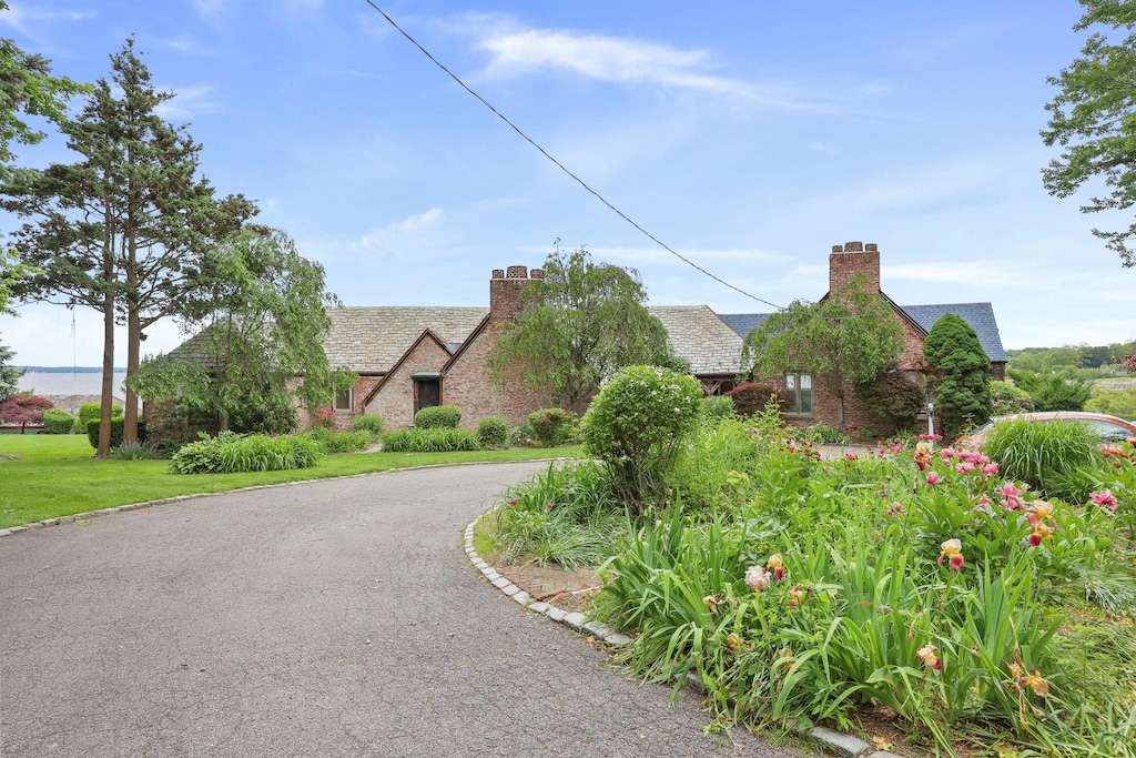 69 Cornwells Bch, Sands Point, NY 11050 - english style home featuring a chimney, curved driveway, and stone siding