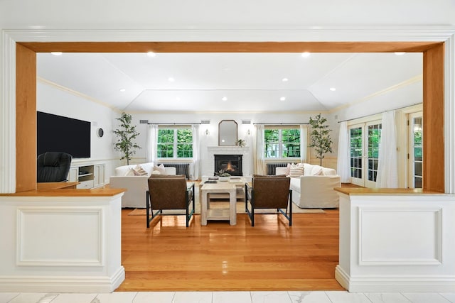 125 Park Ln, West Harrison, NY 10604 - living area with lofted ceiling, radiator heating unit, a glass covered fireplace, crown molding, and light wood-type flooring