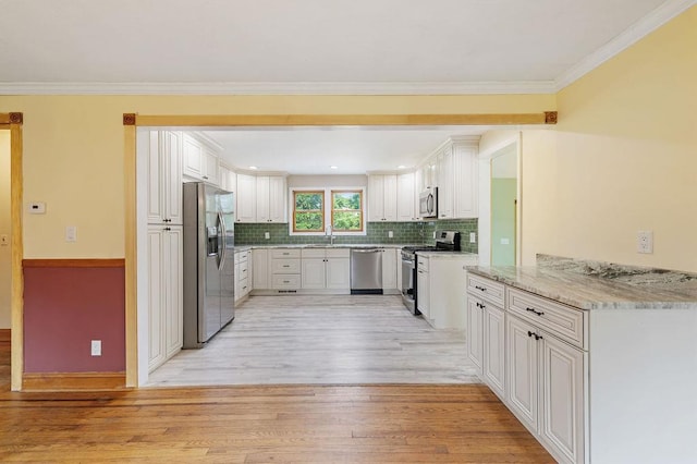 4 W Burda Pl, New City, NY 10956 - kitchen featuring appliances with stainless steel finishes, light wood-style floors, tasteful backsplash, light stone countertops, and crown molding
