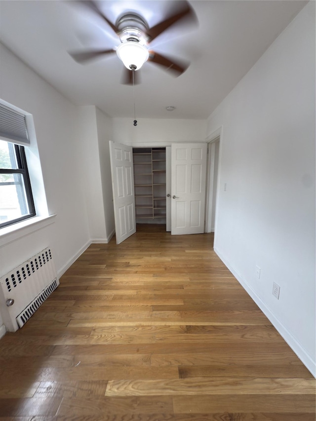 240 Halstead Ave Unit C8, Harrison, NY 10528 - unfurnished bedroom featuring radiator heating unit, a closet, light wood-type flooring, baseboards, and ceiling fan