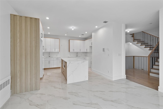 244 Blauvelt Rd Unit 213, Monsey, NY 10952 - kitchen featuring a kitchen island, recessed lighting, radiator, white cabinetry, and light marble finish floors