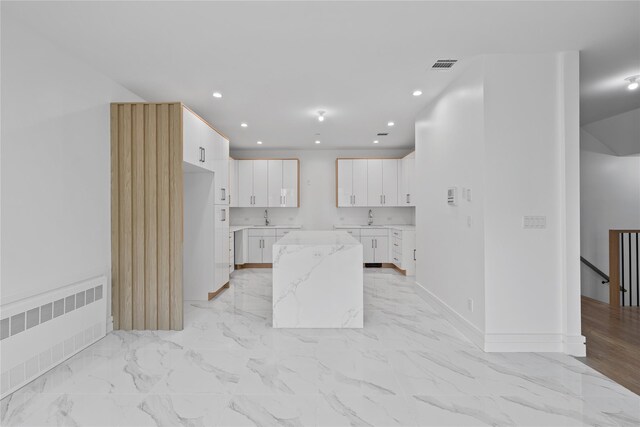 244 Blauvelt Rd Unit 213, Monsey, NY 10952 - kitchen featuring radiator heating unit, recessed lighting, white cabinetry, light marble finish floors, and light stone counters