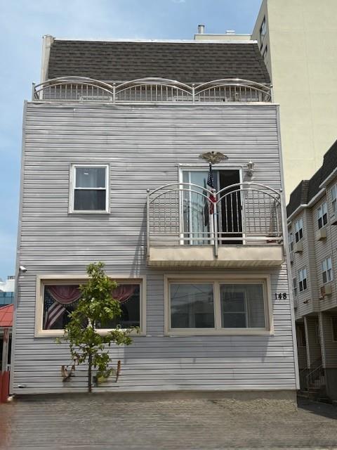 148 Bch 97th St, Rockaway Beach, NY 11693 - rear view of house featuring a balcony and a shingled roof