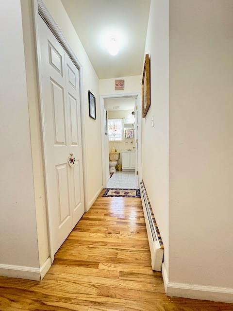 148 Bch 97th St, Rockaway Beach, NY 11693 - hallway featuring baseboard heating, light wood-style flooring, and baseboards