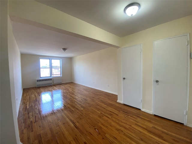 83-36 Beverly Rd Unit 5A, Kew Gardens, NY 11415 - unfurnished room featuring radiator heating unit, wood finished floors, and baseboards