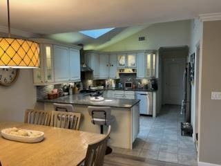 738 Craft Ave, Franklin Square, NY 11010 - kitchen with a peninsula, glass insert cabinets, vaulted ceiling, a skylight, and dark countertops