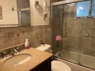 738 Craft Ave, Franklin Square, NY 11010 - bathroom featuring toilet, vanity, combined bath / shower with glass door, wainscoting, and tile walls