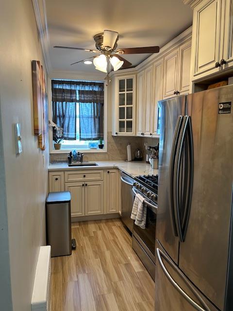 504 Merrick Rd Unit 4E, Lynbrook, NY 11563 - kitchen with stainless steel appliances, cream cabinetry, light countertops, and ornamental molding