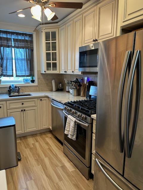 504 Merrick Rd Unit 4E, Lynbrook, NY 11563 - kitchen with appliances with stainless steel finishes, cream cabinetry, ceiling fan, light countertops, and glass insert cabinets