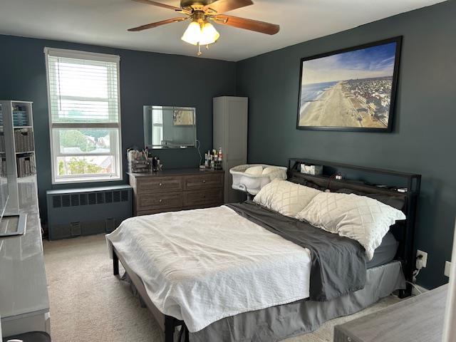 504 Merrick Rd Unit 4E, Lynbrook, NY 11563 - bedroom featuring radiator, carpet, and a ceiling fan