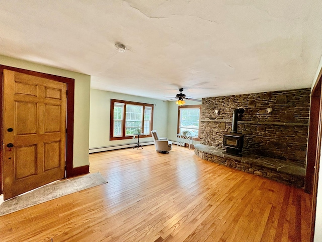 13 Rockland Rd, Roscoe, NY 12776 - unfurnished living room with baseboard heating, light wood finished floors, a wood stove, and a ceiling fan