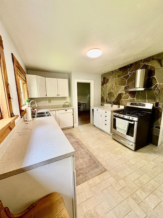 13 Rockland Rd, Roscoe, NY 12776 - kitchen featuring stainless steel range with gas cooktop, backsplash, light countertops, white cabinets, and wall chimney exhaust hood