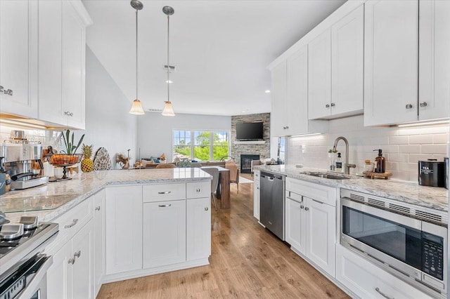 24 Hearthstone Ct Unit 24, Farmingdale, NY 11735 - kitchen featuring stainless steel appliances, backsplash, a stone fireplace, and white cabinetry