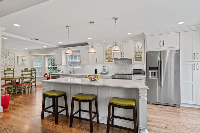 81 Hidden Ridge Dr, Syosset, NY 11791 - kitchen with stainless steel appliances, crown molding, light countertops, light wood-type flooring, and a kitchen breakfast bar