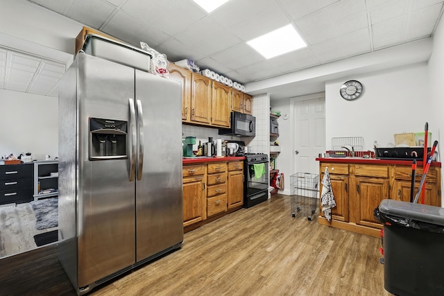 305 Columbus Ave, Harrison, NY 10604 - kitchen featuring black appliances, light wood-style flooring, brown cabinets, and backsplash