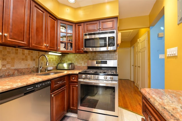 1319 E 86th St, Brooklyn, NY 11236 - kitchen with stainless steel appliances, light stone countertops, backsplash, glass insert cabinets, and light tile patterned floors