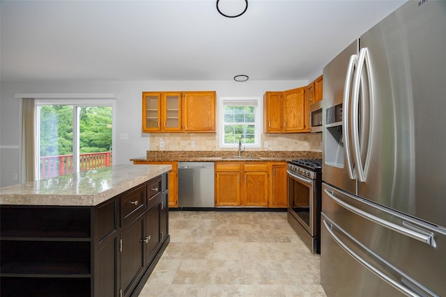 15 Pond St, Poughkeepsie, NY 12603 - kitchen with appliances with stainless steel finishes, a sink, decorative backsplash, glass insert cabinets, and brown cabinetry