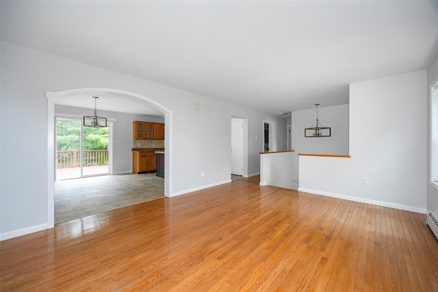 15 Pond St, Poughkeepsie, NY 12603 - unfurnished living room with light wood-style floors, a chandelier, arched walkways, and baseboards