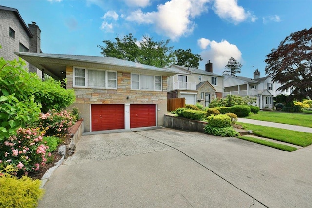 8519 212th St, Hollis Hills, NY 11427 - view of front of house with concrete driveway, stone siding, and an attached garage