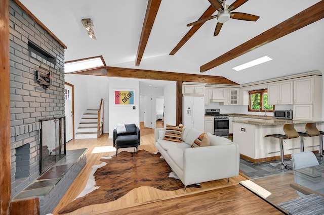 39 Cliff Rd, Greenwood Lake, NY 10925 - living area with a brick fireplace, light wood finished floors, stairs, and ceiling fan
